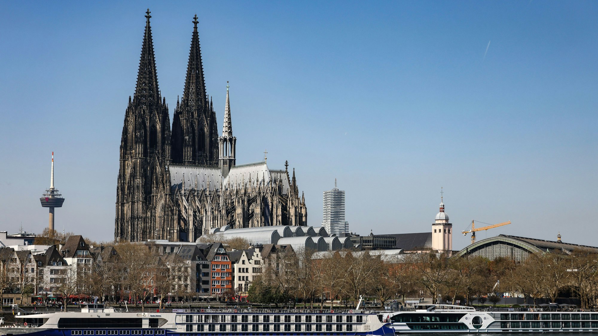 Ein Boot fährt bei sonnigem Wetter am Kölner Dom vorbei über den Rhein.