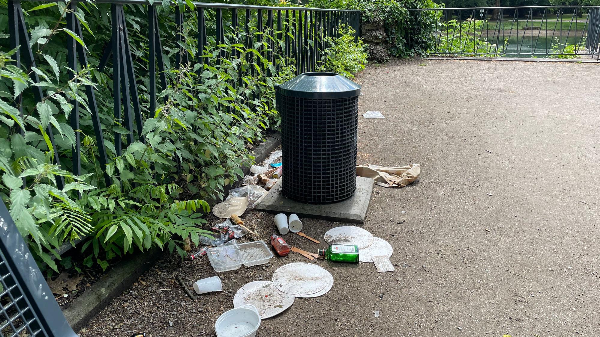Müll liegt achtlos um einen Mülleimer im Volksgarten