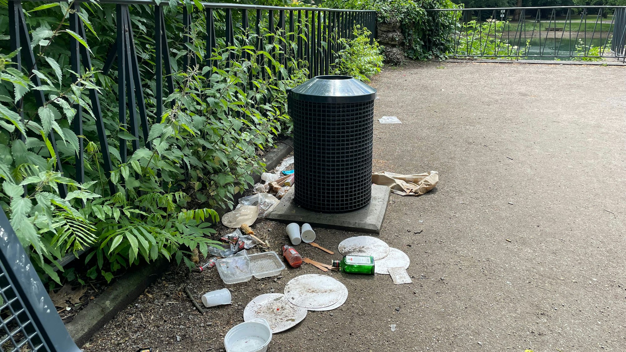 Müll liegt achtlos um einen Mülleimer im Volksgarten