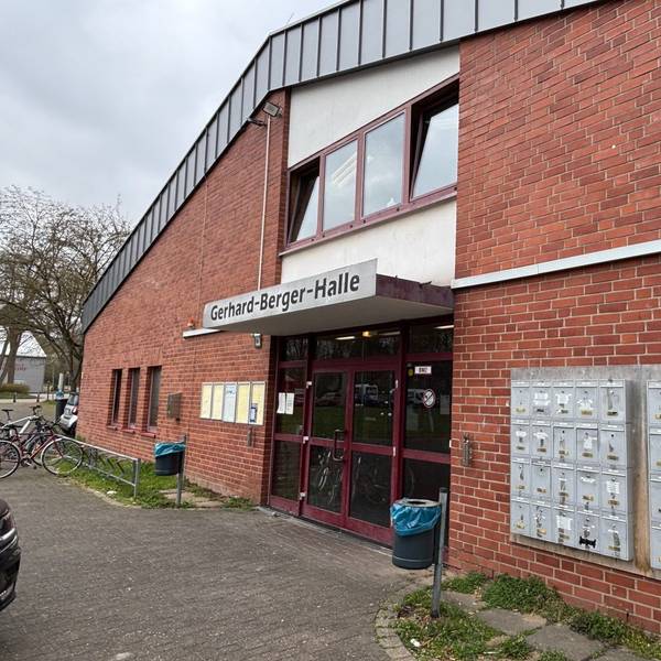 Auf dem Bild ist eine Turnhalle zu sehen. Neben dem Eingang sind Briefkästen für die dort untergebrachten Menschen montiert.