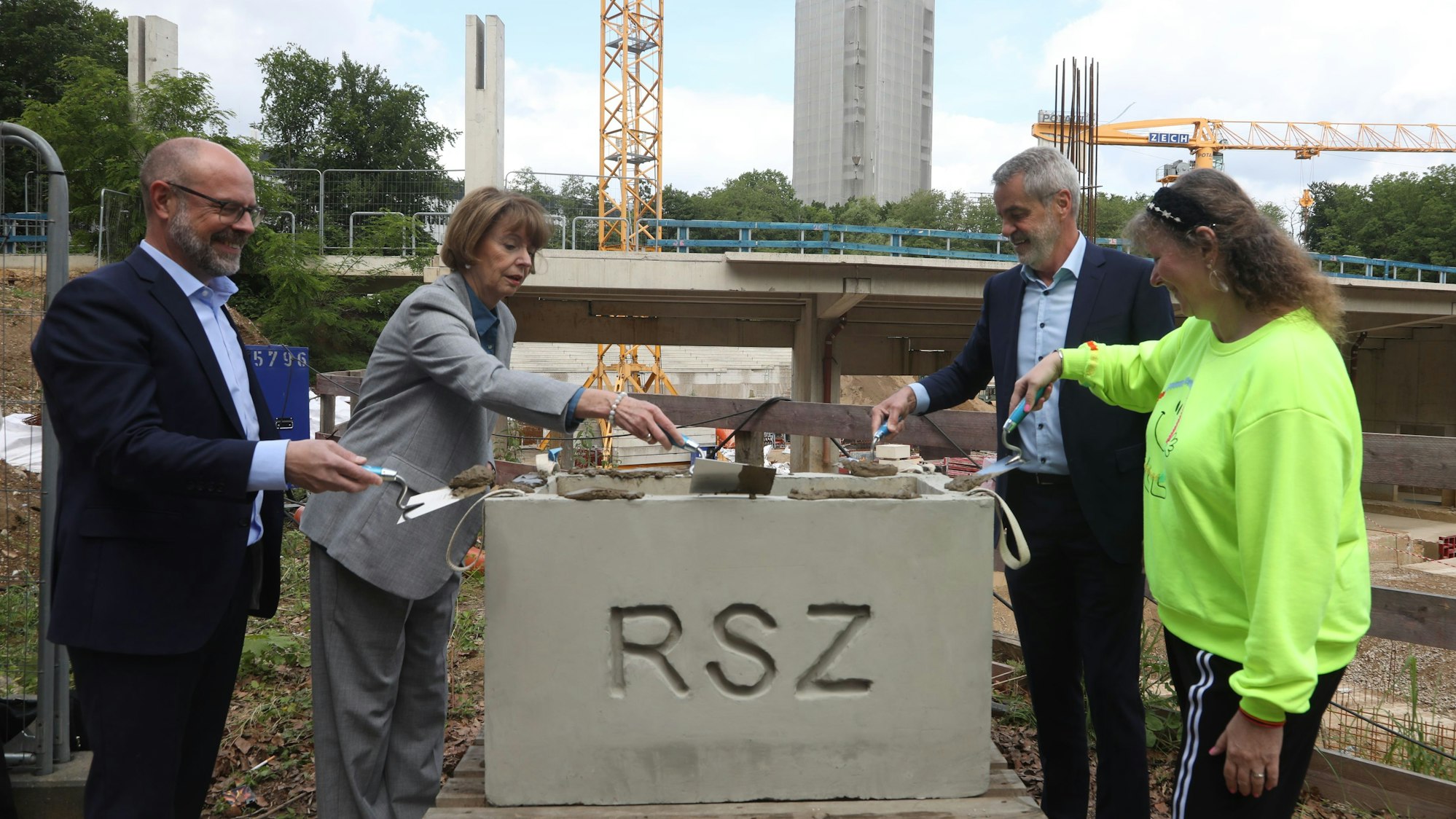 Oberbürgermeisterin Henriette Reker (2. v.l.), die Sportstätten-Geschäftsführer Lutz Wingerath (l.) und Frank Höller und Andrea Milz, NRW-Staatssekretärin Sport, bestreichen den Grundstein für das neue Albert-Richter-Velodrom mit Zement.