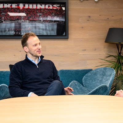 Zwei ehemalige Fußballprofis sitzen an einem Tisch zusammen und besprechen sich.