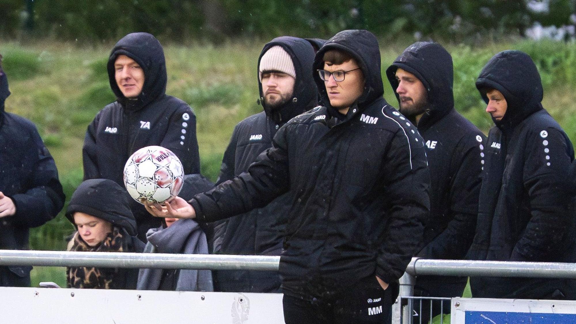 Das Bild zeigt den Trainer an der Seitenlinie. Er hält einen Ball in der Hand.