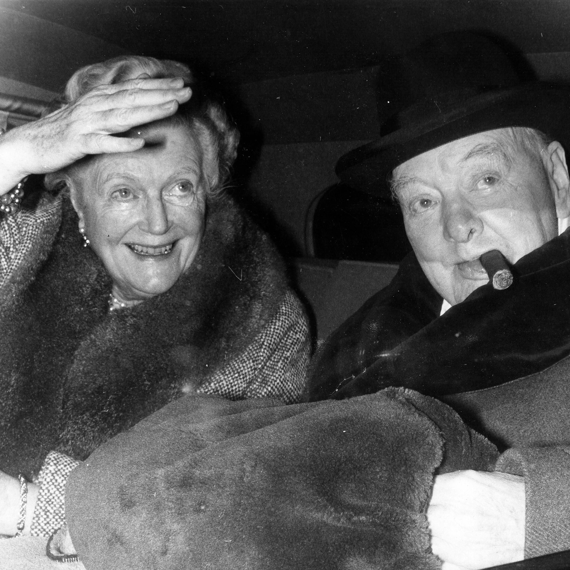 Die Churchills auf der Rückbank im Wagen: Sie winkt und lacht, er raucht Zigarre und hält ihren Muff.