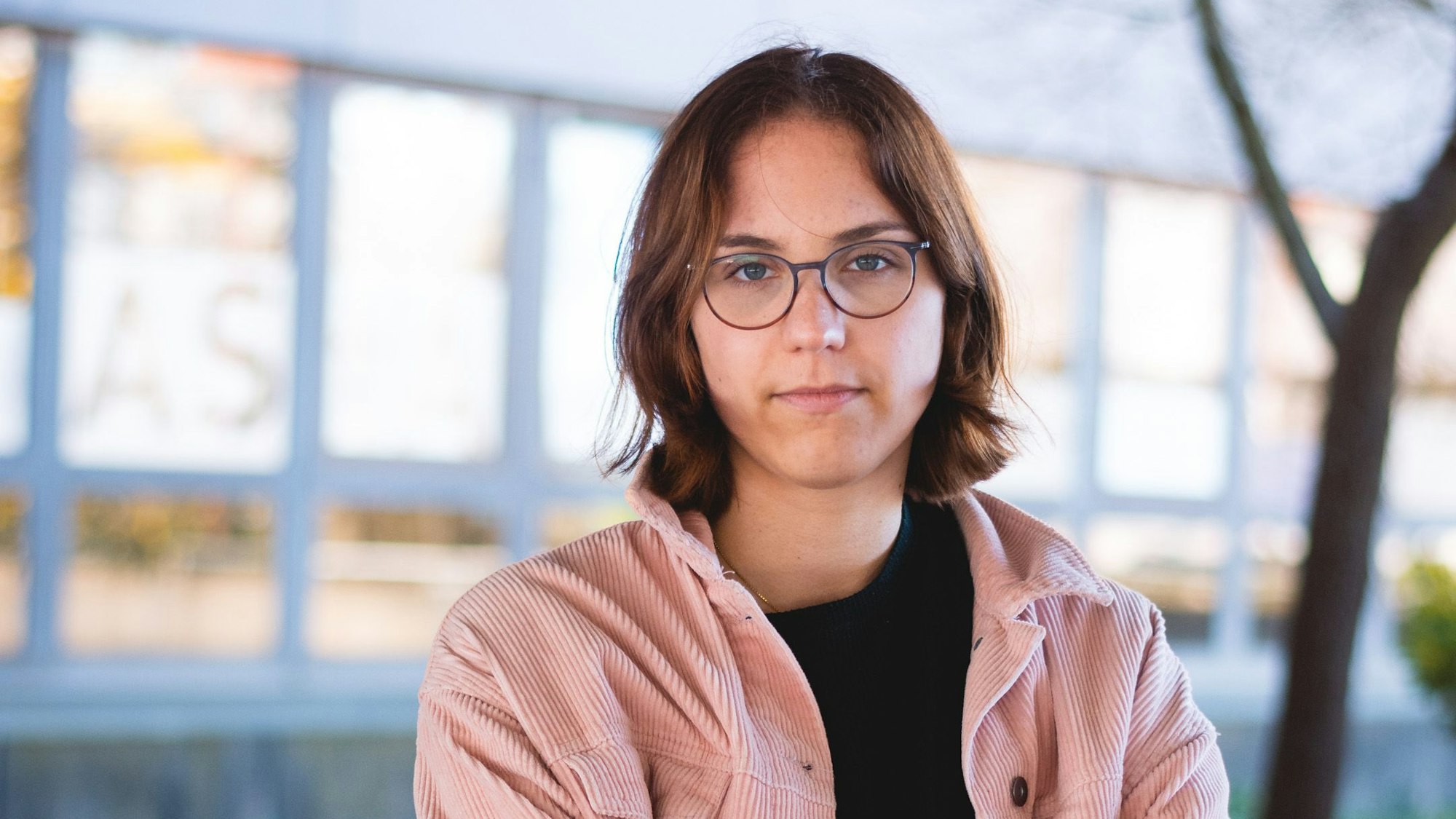 Nicola Dichant ist im Porträt zu sehen: eine junge Frau mit Brille und halblangen, dunkelbraunen Haaren.