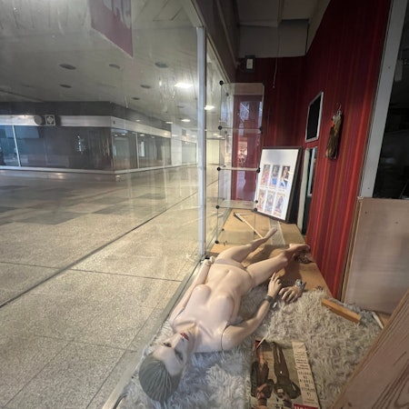 Eine Schaufensterpuppe liegt in einem leeren Schaufenster der City C