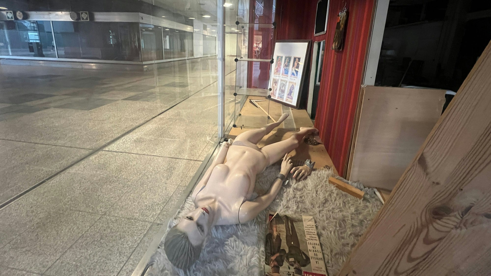 Eine Schaufensterpuppe liegt in einem leeren Schaufenster der City C