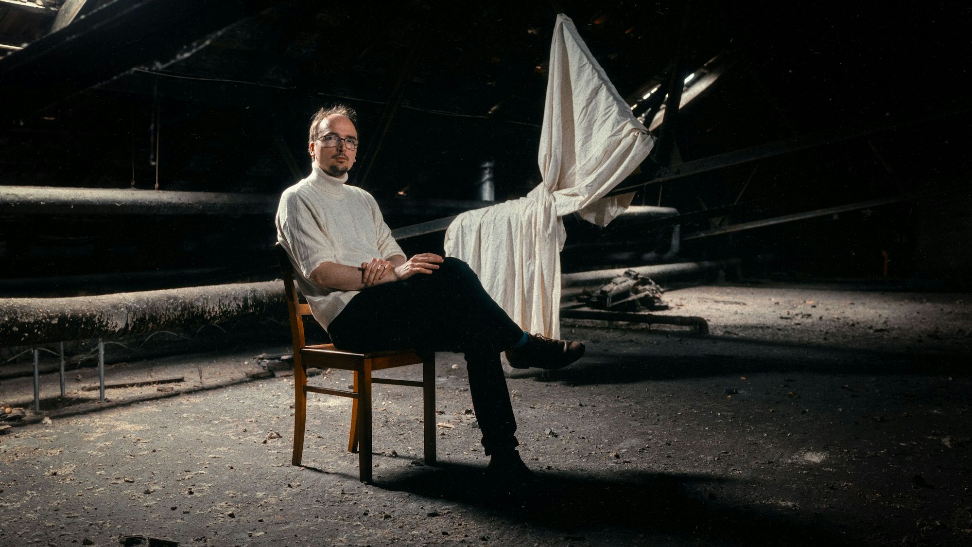 Constantin Krahmer sitzt auf einem Dachboden.