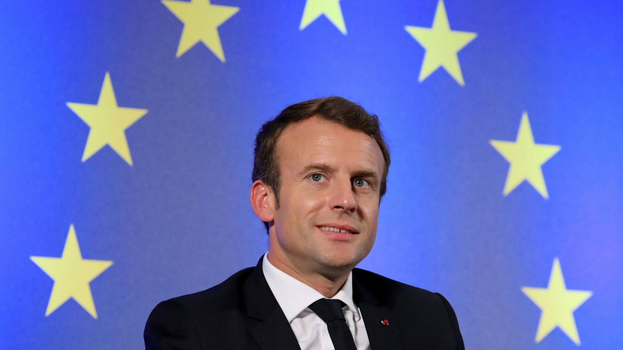 (FILES) This file photo taken on October 10, 2017 shows French President Emmanuel Macron sitting in front of a flag of the European Union during an open debate on Europe at the Goethe University in Frankfurt am Main, western Germany.
French President Emmanuel Macron will be awarded the 2018 International Charlemagne Prize of Aachen (Karlspreis), the city of Aachen and the Charlemagne Prize committee board announced on December 8, 2017. The prize, named for Charlemagne, the Franconian king revered by his contemporaries as the ‘Father of Europe’, is awarded for work done in the service of European unification. / AFP PHOTO / LUDOVIC MARIN