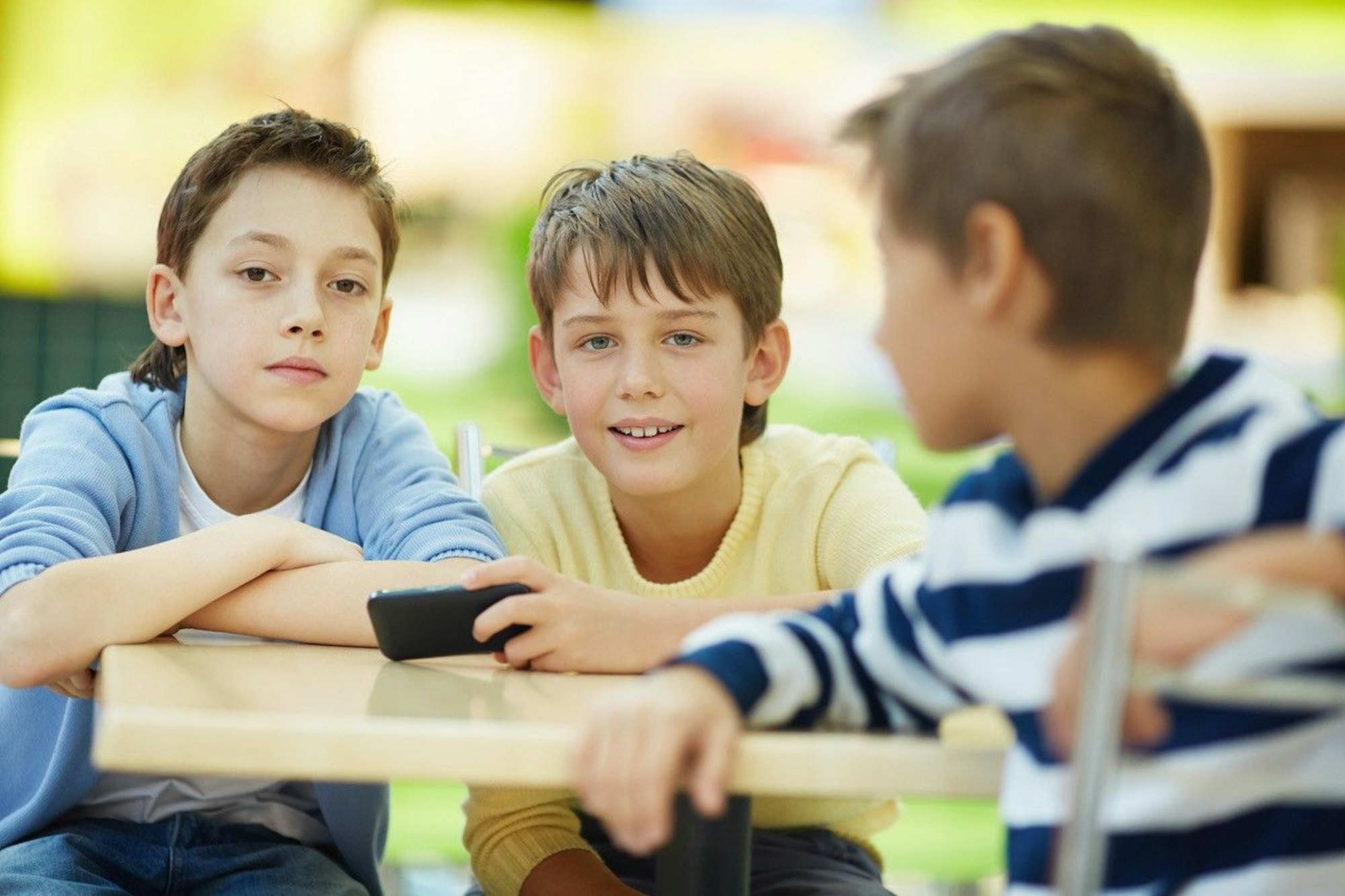 Drei Jungs sitzen an einem Tisch und unterhalten sich freundlich.