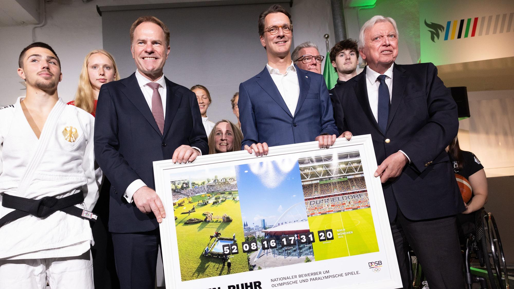 NRW-Ministerpräsident Hendrik Wüst (2. v. r, CDU), Volker Bouffier (r.), Vorstand für besondere Aufgaben des DOSB, und Stephan Keller (CDU), Oberbürgermeister von Düsseldorf, zusammen mit Sportlerinnen und Sportlern bei der Vorstellung des Konzepts einer Olympia-Bewerbung mit der Rhein-Ruhr-Region.
