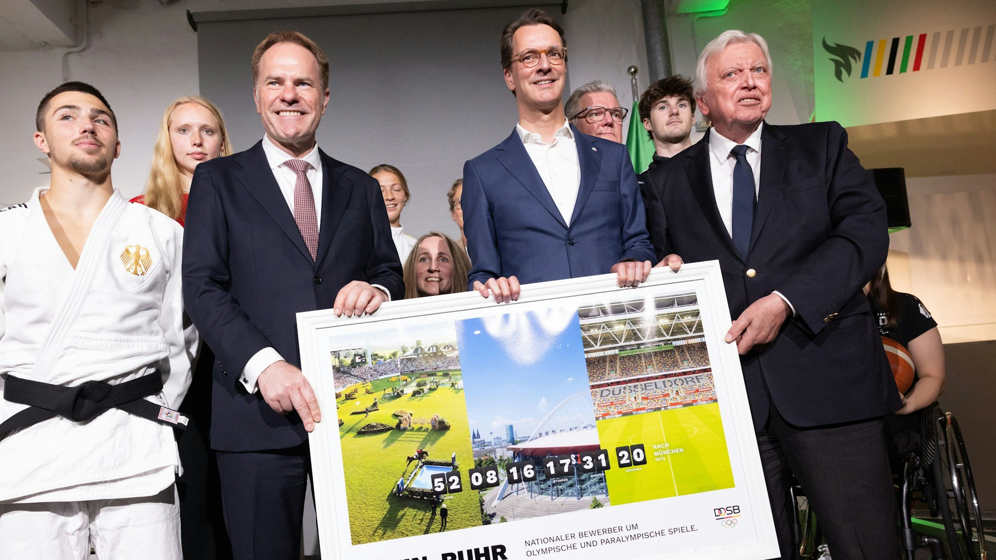 NRW-Ministerpräsident Hendrik Wüst (2. v. r, CDU), Volker Bouffier (r.), Vorstand für besondere Aufgaben des DOSB, und Stephan Keller (CDU), Oberbürgermeister von Düsseldorf, zusammen mit Sportlerinnen und Sportlern bei der Vorstellung des Konzepts einer Olympia-Bewerbung mit der Rhein-Ruhr-Region.