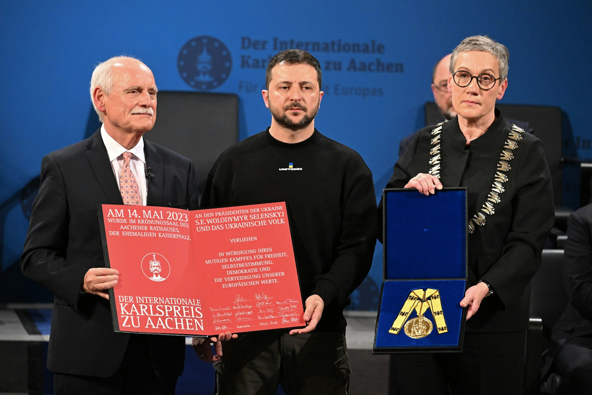 14.05.2023, Nordrhein-Westfalen, Aachen: Der ukrainische Präsident Wolodymyr Selenskyj (M) erhält den Karlspreis für Verdienste um die Einheit Europas von der Oberbürgermeisterin von Aachen Sibylle Keupen (r, parteilos) und Jürgen Linden, Vorsitzender der Gesellschaft zur Verleihung des Internationalen Karlspreises zu Aachen. Foto: Federico Gambarini/dpa-Pool/dpa +++ dpa-Bildfunk +++