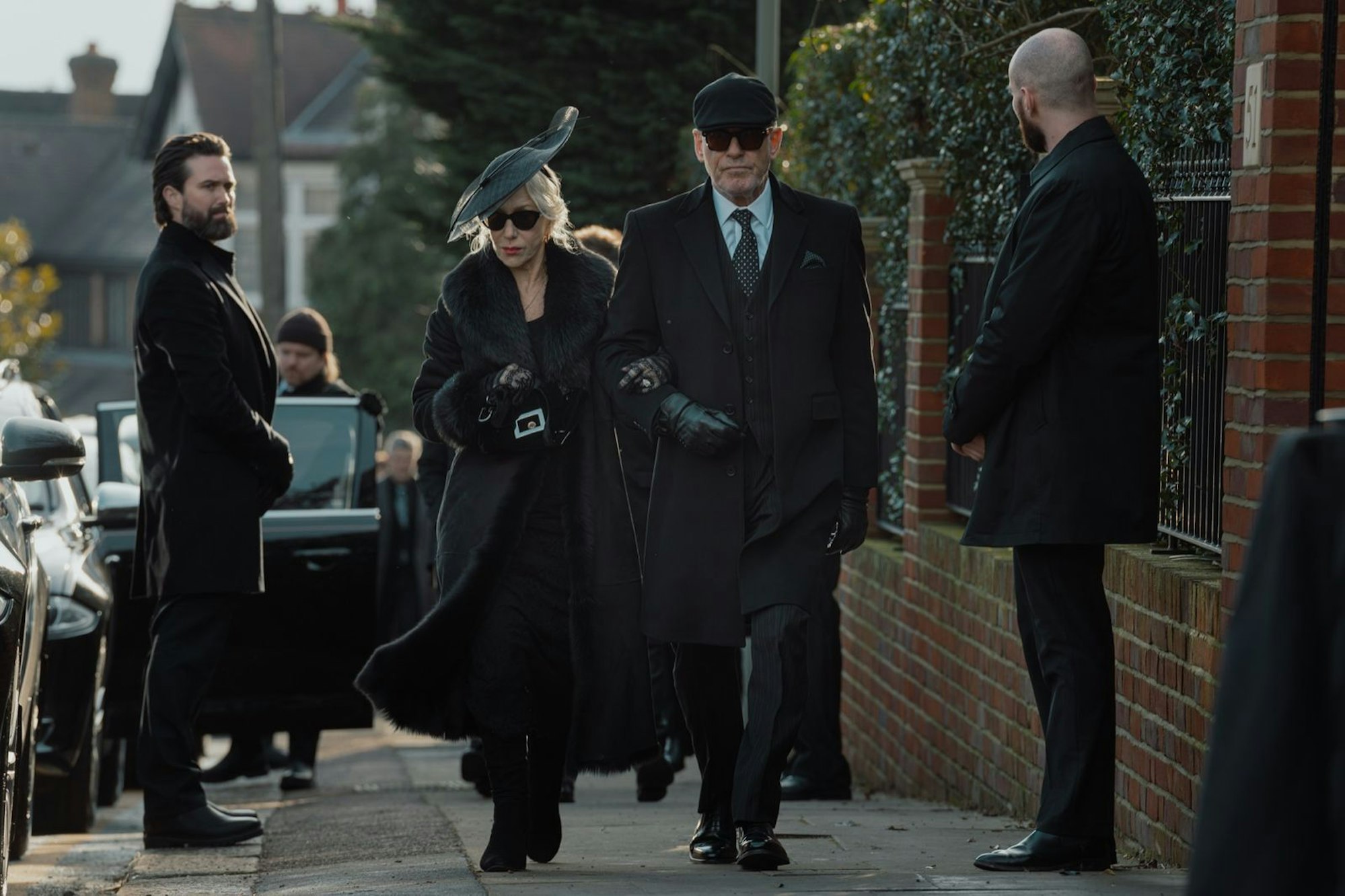 Gestorben wird immer, erst recht in einer Gangsterserie: Die Carrigans (Helen Mirren, Pierce Brosnan) müssen auf eine Beerdigung. (Bild: ©2025 Viacom International Inc. / Paramount + / Luke Varley)