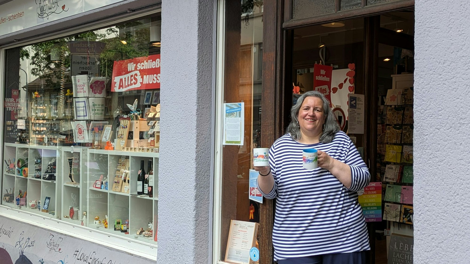 Eine Frau steht mit Bechern in der Hand in der Tür eines Geschäfts
