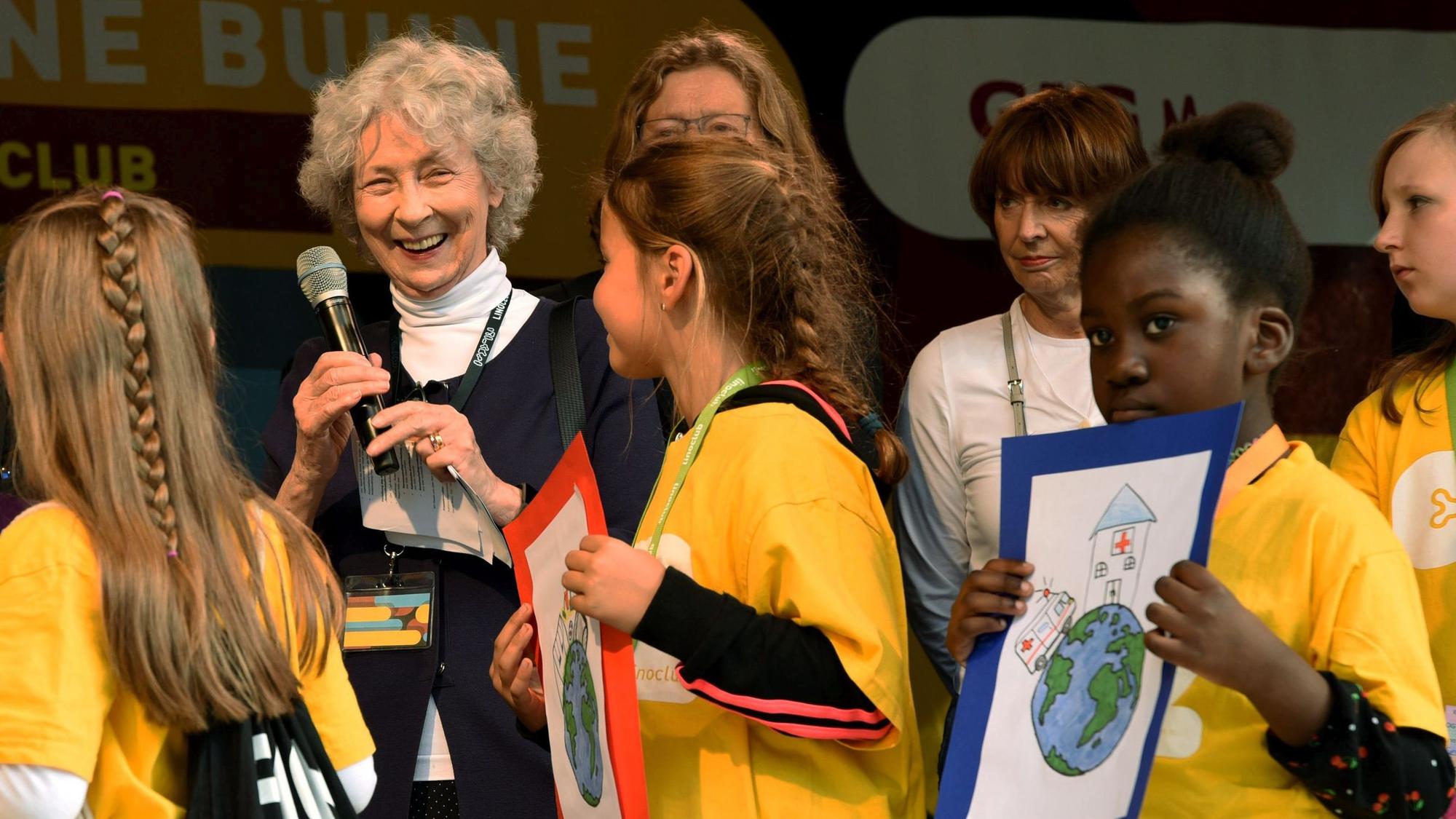Hedwig Neven DuMont ist auch in diesem Jahr wieder gemeinsam mit Henriette Reker Schirmherrin des Weltkindertags in Köln. Sie steht umringt von Kindern auf der Bühne.