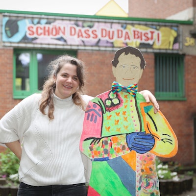 Die Leiterin des Don-Bosco-Clubs in Mülheim Magdalena Keil umarmt eine Pappfigur des Namensgebers der Jugendeinrichtung.