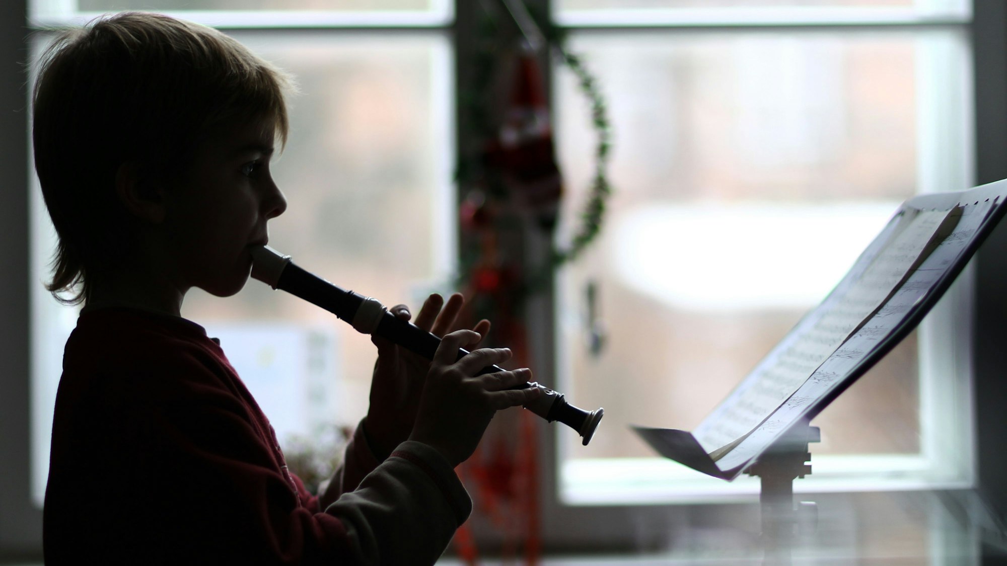 Das Foto zeigt einen Musikschüler, der auf einer Blockflöte spielt.