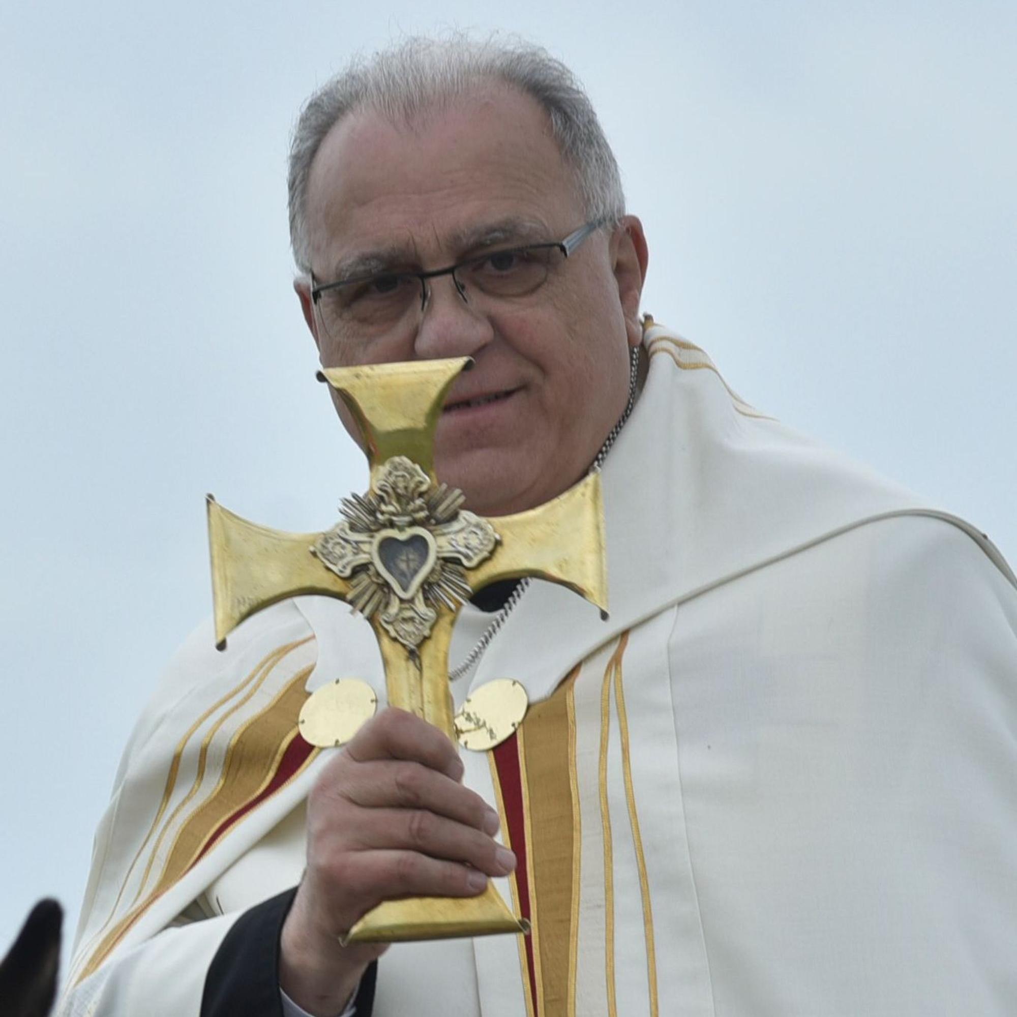 Ein Pfarrer hält ein Kreuz.
