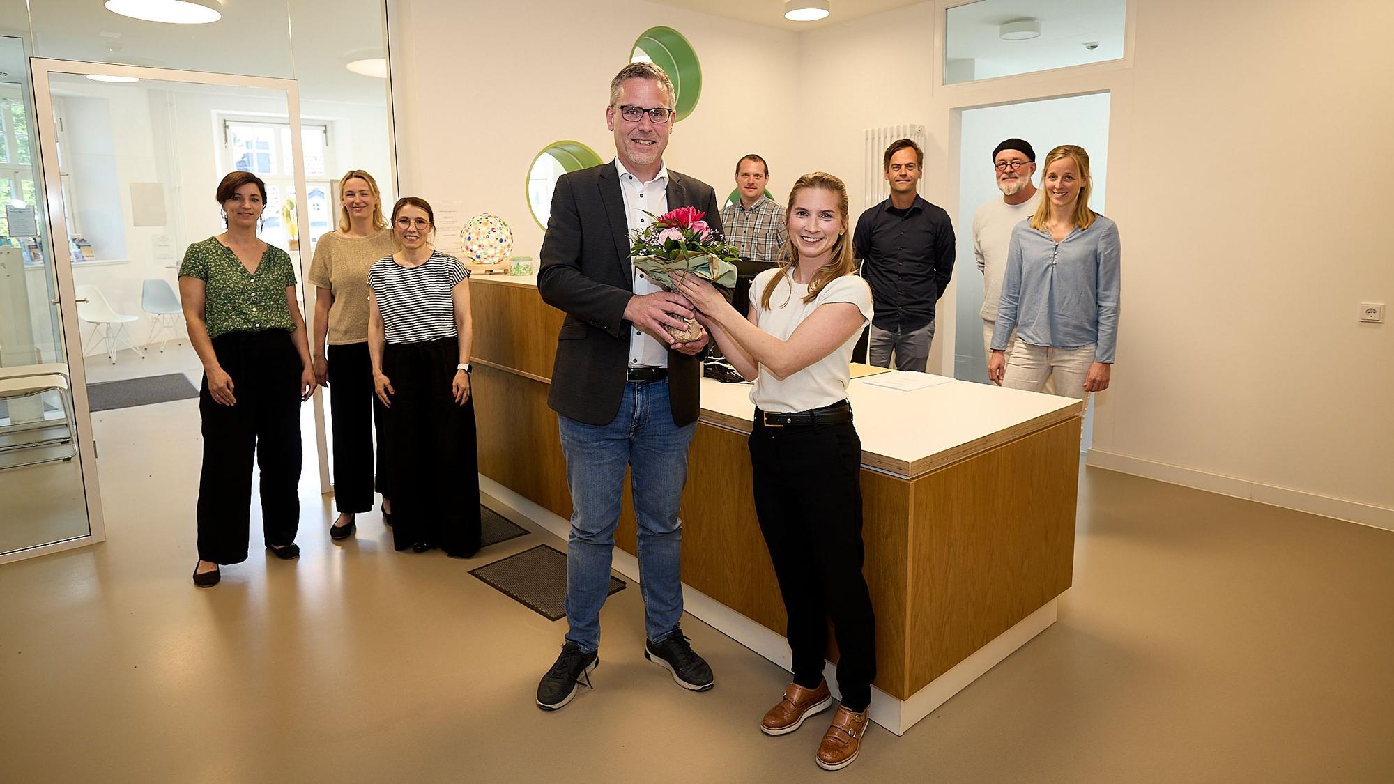 Das Team des Ärztezentrums Nettersheim steht im Hintergrund. Vorne überreicht Bürgermeister Norbert Crump Blumen an Caroline Lenz, die das Team als Gynäkologin verstärken wird.