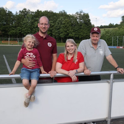 Blick auf drei Erwachsene und ein Kind, die auf dem Sportplatz in Frielingsdorf stehen.