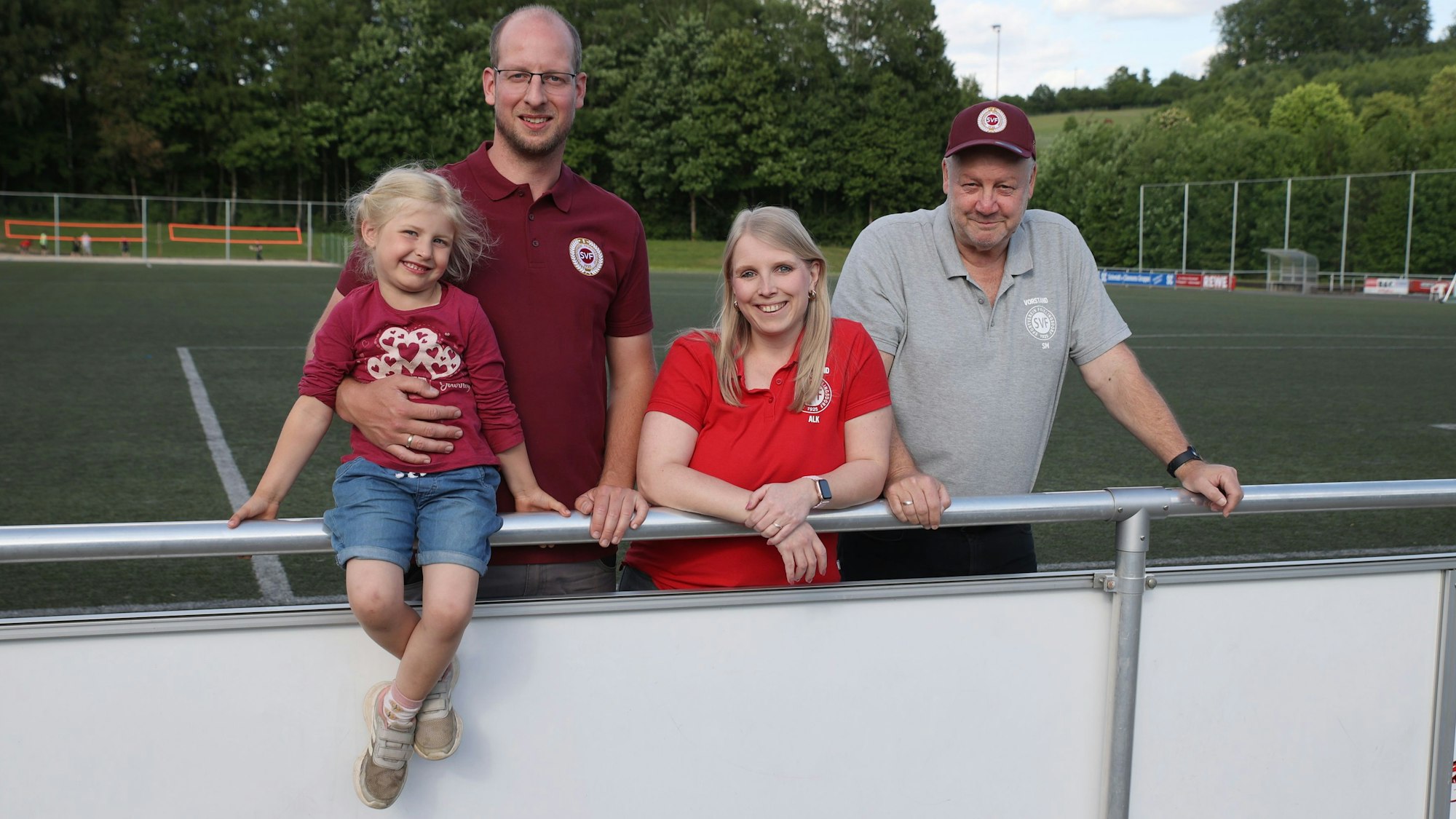 Blick auf drei Erwachsene und ein Kind, die auf dem Sportplatz in Frielingsdorf stehen.