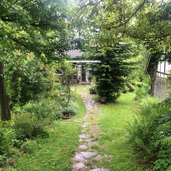 Ein kleines Haus steht am Ende eines kleinen Weges, der durch einen idyllischen Garten führt.