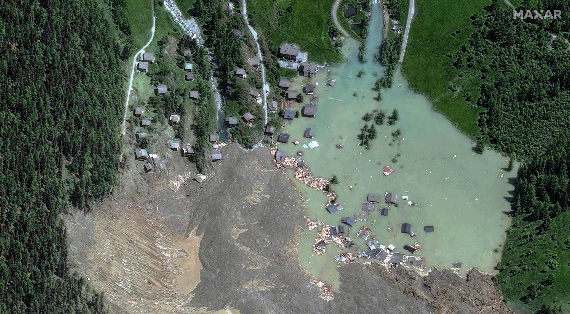 HANDOUT - 29.05.2025, Schweiz, Blatten: Dieses von Maxar Technologies zur Verfügung gestellte Satellitenbild zeigt das Dorf Blatten in der Schweiz am 29. Mai 2025, nachdem es durch eine Schlammlawine zerstört wurde und sich ein See gebildet hat. Das Flussbett der Lonza ist blockiert. Deshalb bildet sich dort ein See, dessen Pegelstand zeitweise drei Meter in der Stunde stieg. Der See breite sich nun in der Fläche aus. Man rechne damit, dass die immensen Wassermassen den See in den frühen Morgenstunden zum Überlaufen bringen. Foto: -/Maxar Technologies/AP/dpa - ACHTUNG: Nur zur redaktionellen Verwendung im Zusammenhang mit einer Berichterstattung und nur mit vollständiger Nennung des vorstehenden Credits +++ dpa-Bildfunk +++