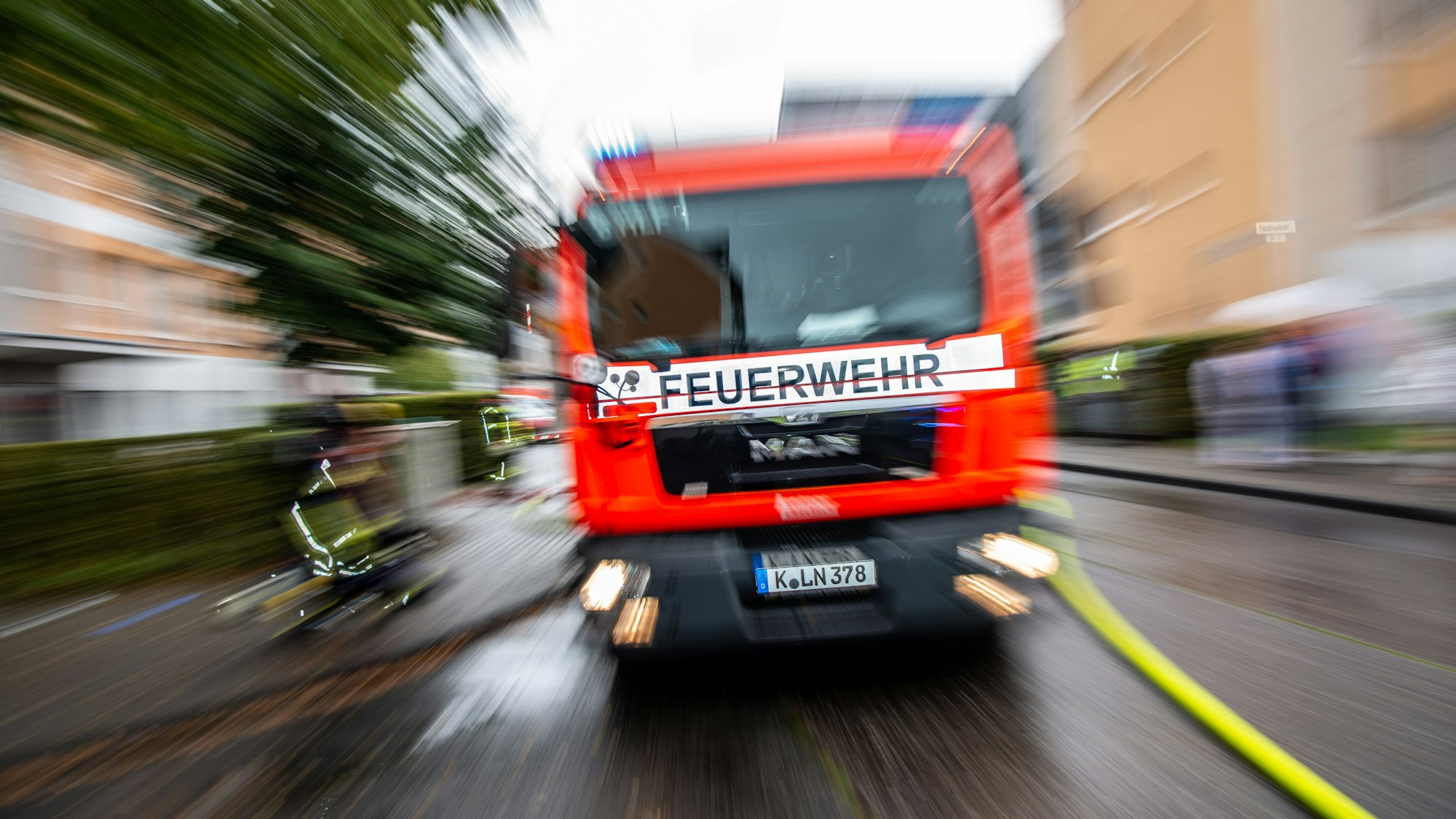 Ein Feuerwehrfahrzeug steht auf einer Straße, daneben ist ein Löschschlauch ausgerollt worden.