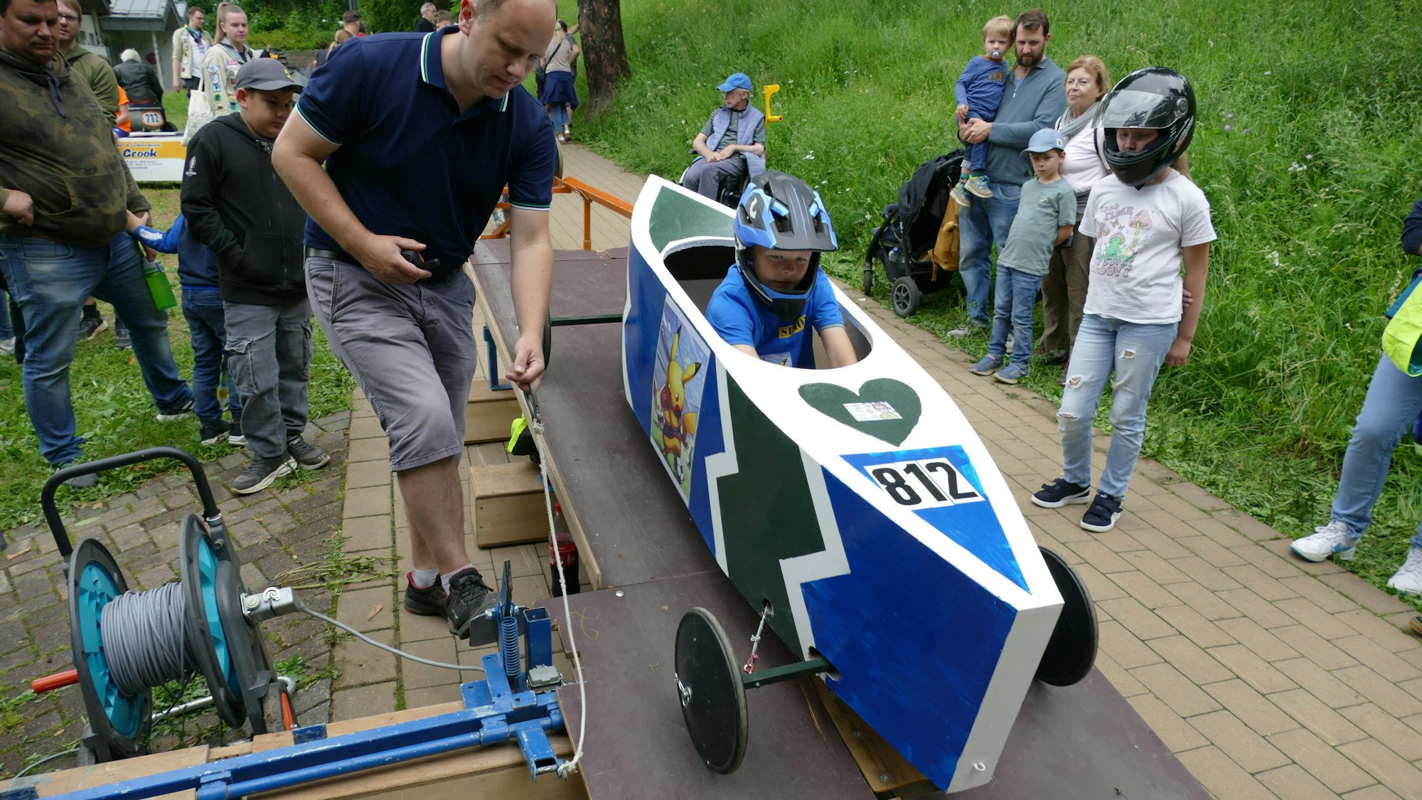 Simon aus Hennef startet mit einer blauen Seifenkiste mit Pokemon Pikachu und Fußball drauf.