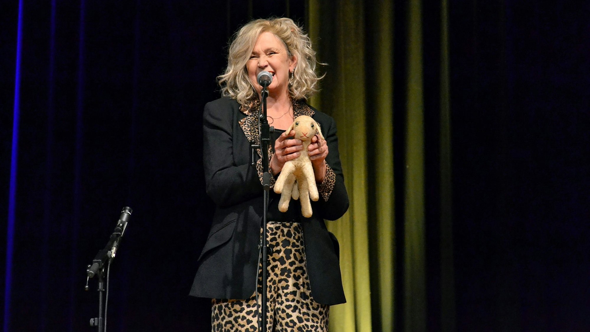 Birgit Breuer steht am Mikro und hält ein Plüschtier in den Händen.