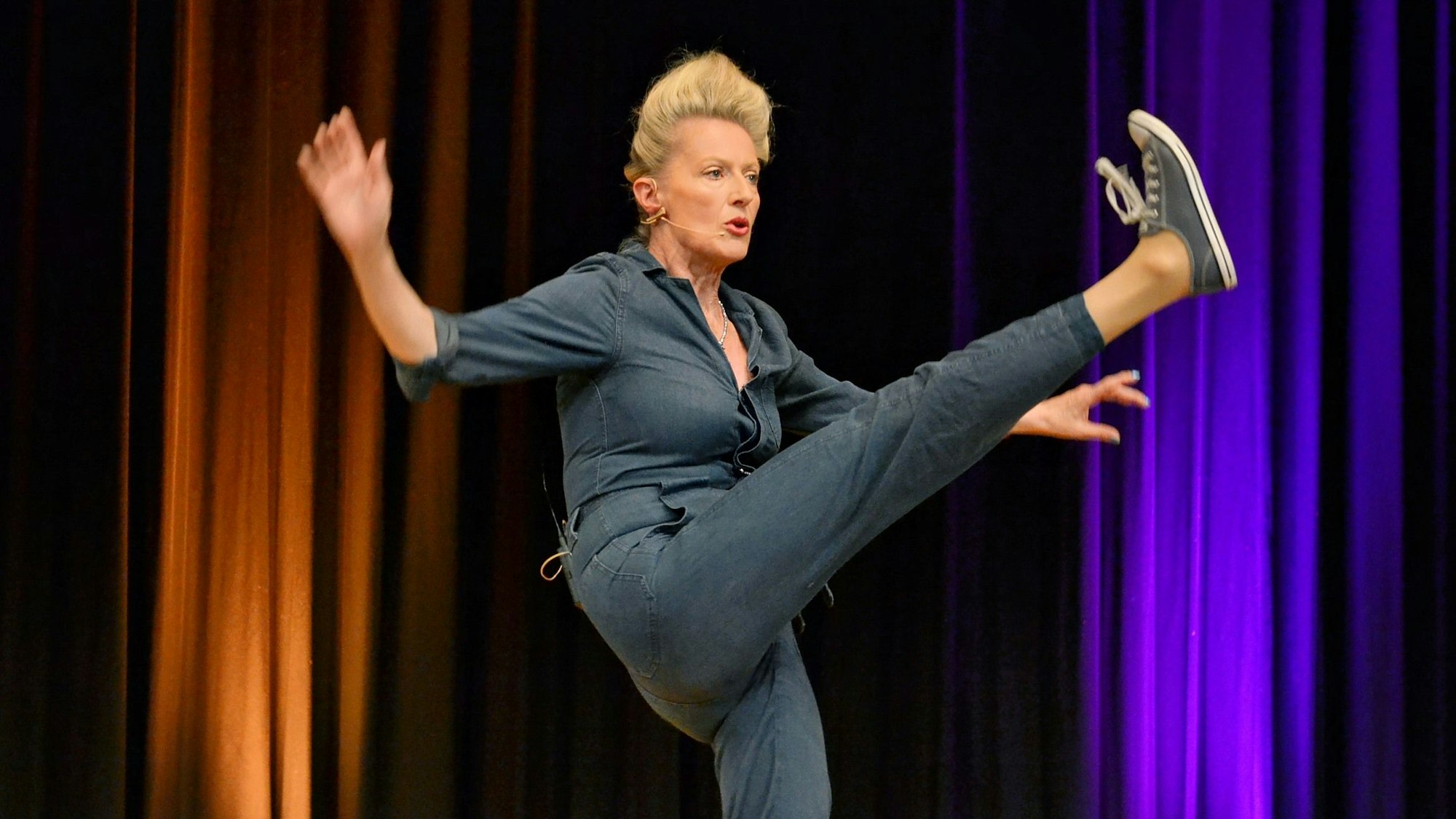 Katharina Hoffmann hebt mit Schwung das linke Bein in die Höhe. Die Arme sind ausgebreitet.