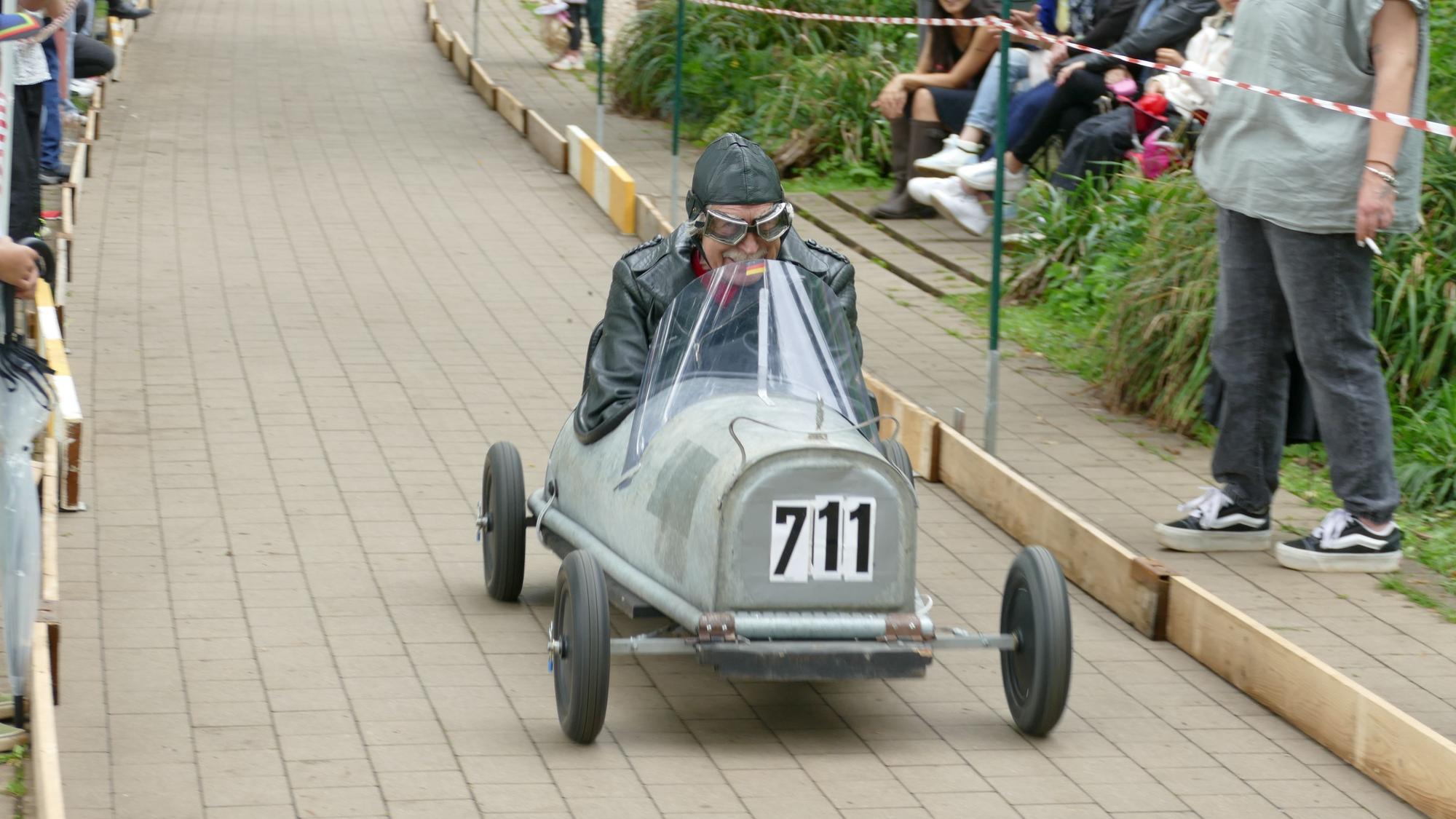 Ein Seifenkistenpilot ist mit einer umgebauten Badewanne beim Rennen unterwegs.