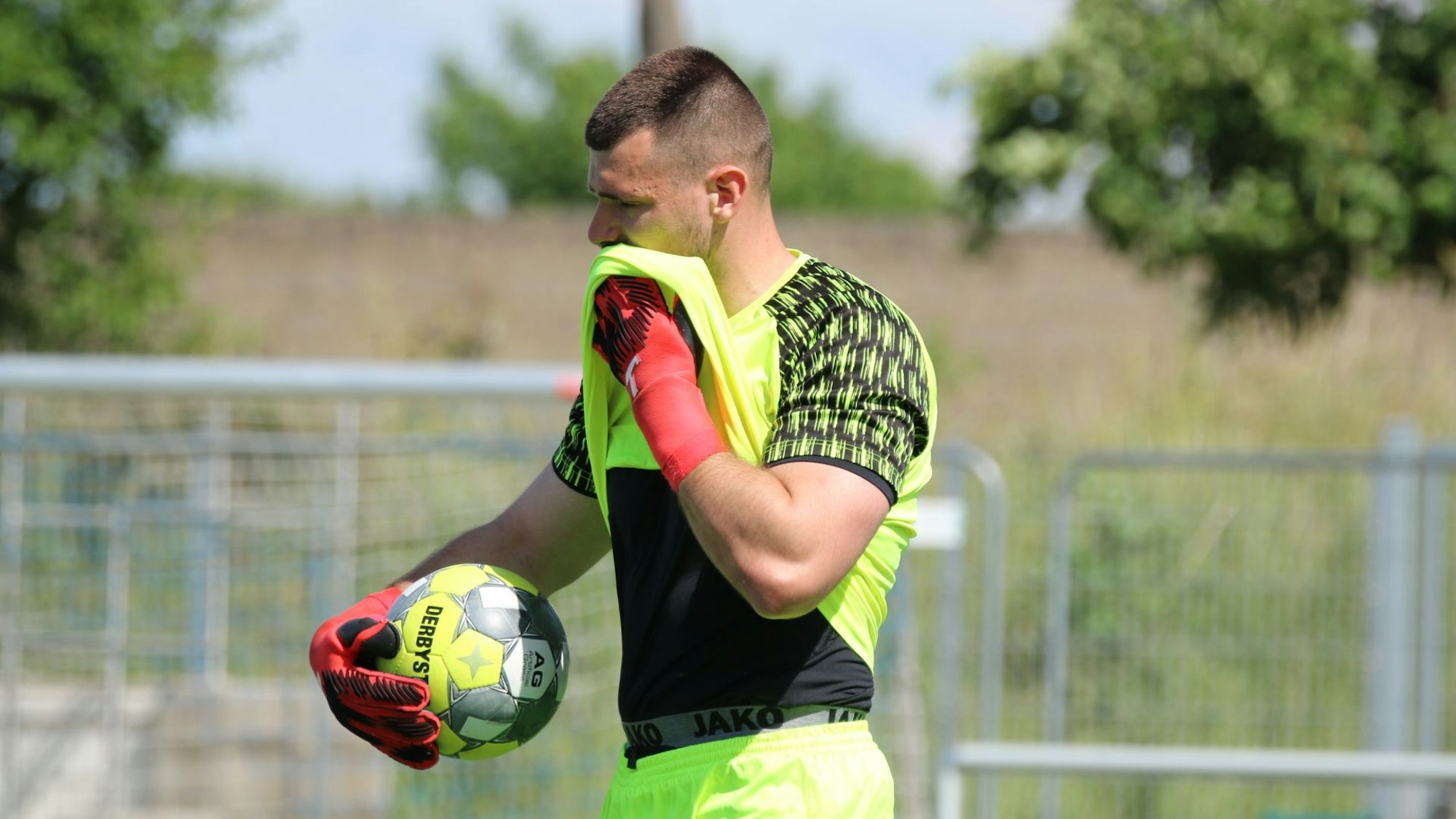 Torwart Eamonn Klein hält in der rechten Hand den Ball, mit der linken reibt er sich seinen Mund am Trikot ab.