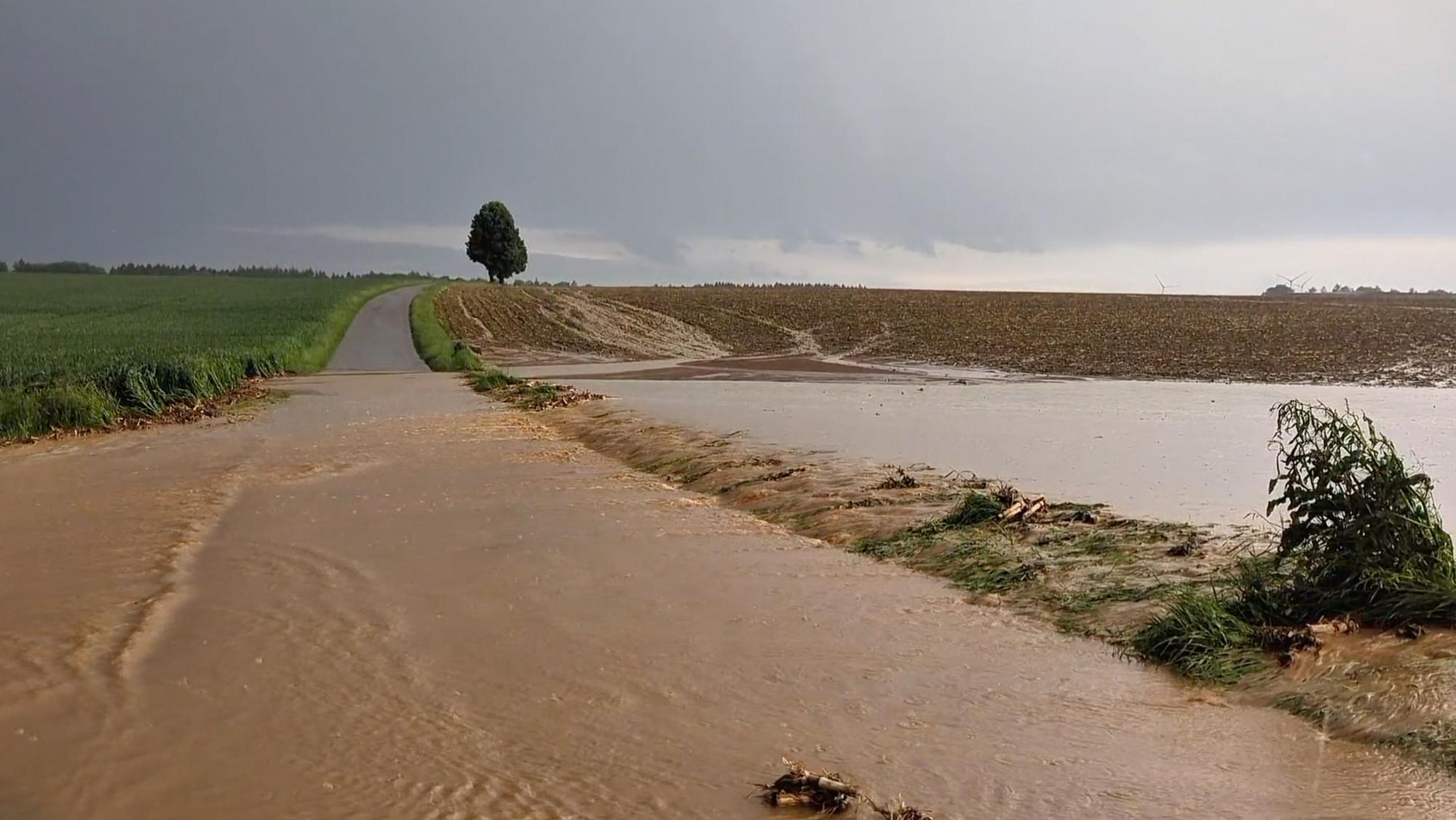 Baden-Württemberg, Berghülen: Oberflächenwasser läuft nach einem starken Gewitter von einem noch nicht bewachsenen Acker quer über einen Weg.