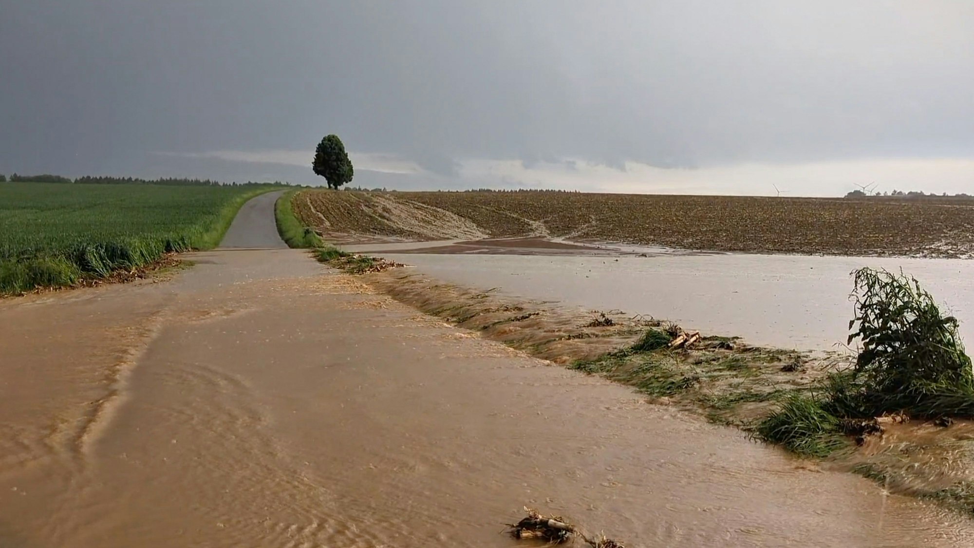 Baden-Württemberg, Berghülen: Oberflächenwasser läuft nach einem starken Gewitter von einem noch nicht bewachsenen Acker quer über einen Weg.