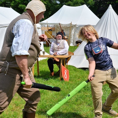 Ein Junge und ein Mann befinden sich im Schaumstoffschlägerduell.