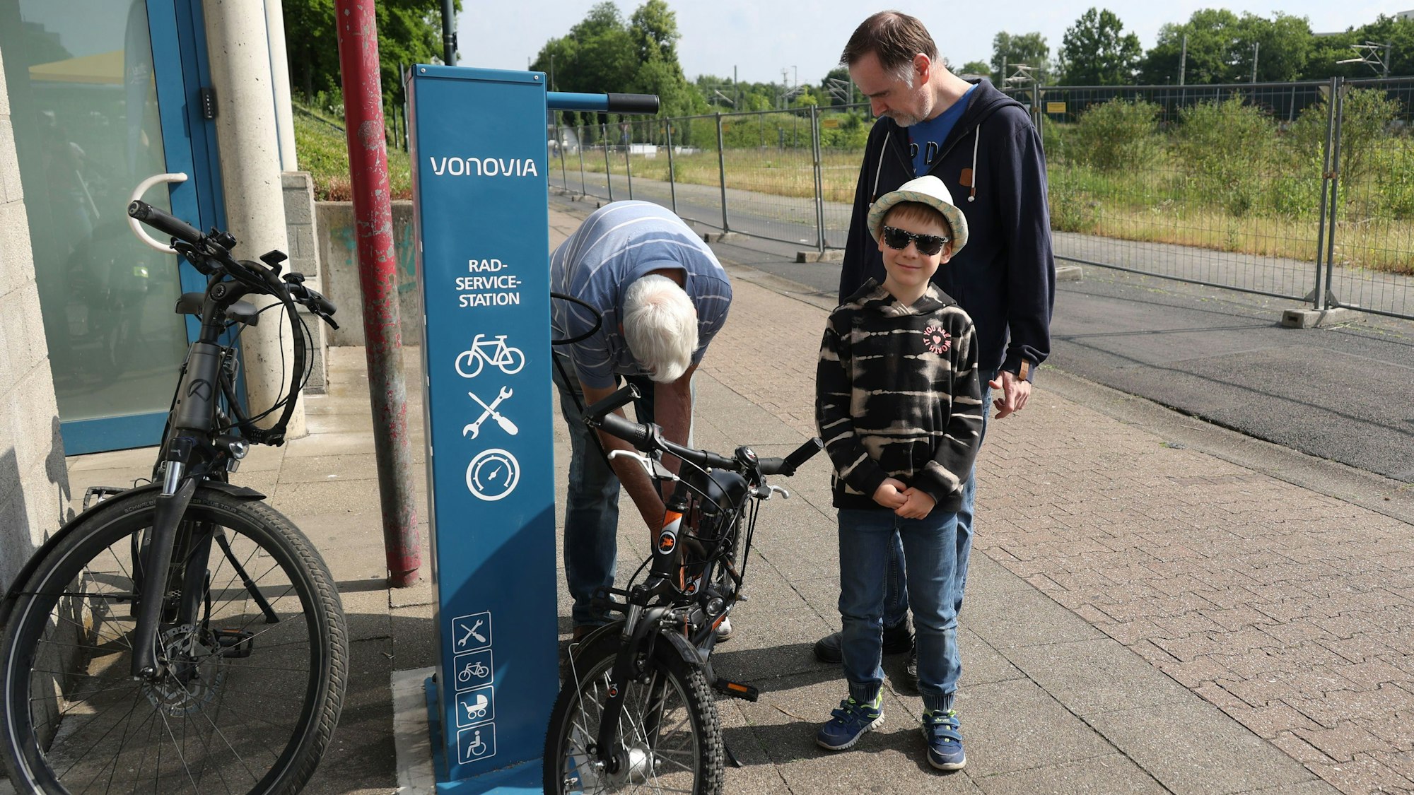 Ein Junge und zwei Erwachsene mit zwei Fahrrädern