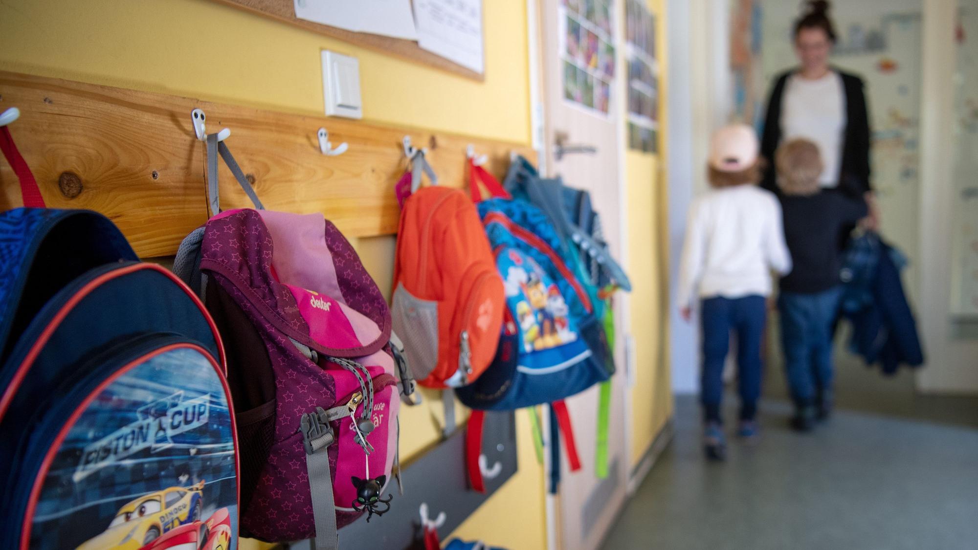 Kinderrucksäcke hängen an einer Garderobe.