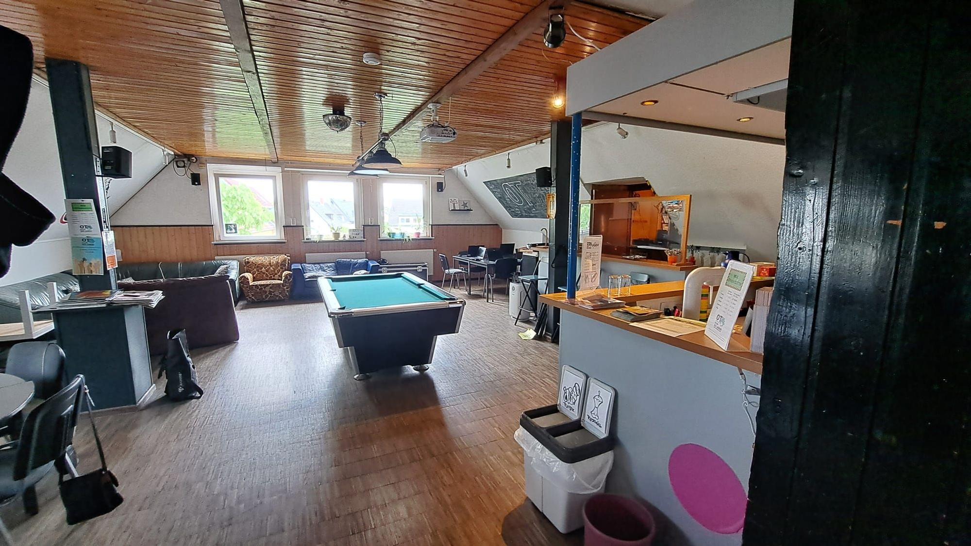 Ein Billardtisch, eine Sitzecke, ein Sofa und ein Sessel stehen in einem großen ausgebauten Dachgeschoss.