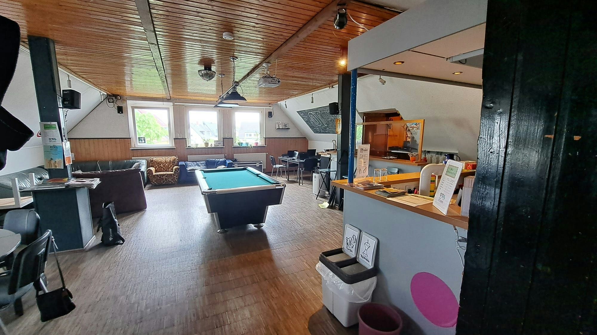 Ein Billardtisch, eine Sitzecke, ein Sofa und ein Sessel stehen in einem großen ausgebauten Dachgeschoss.