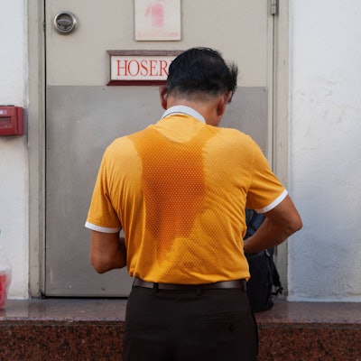 Mann mit Schweißflecken auf dem Shirt.