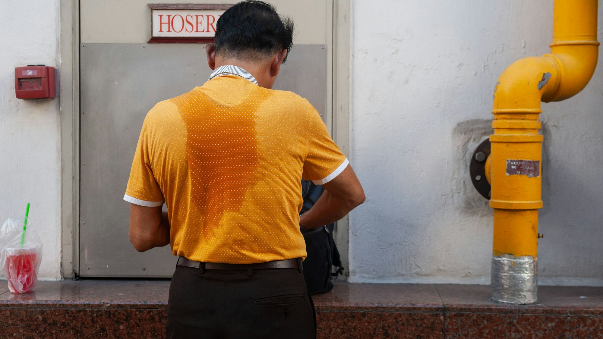 Mann mit Schweißflecken auf dem Shirt.