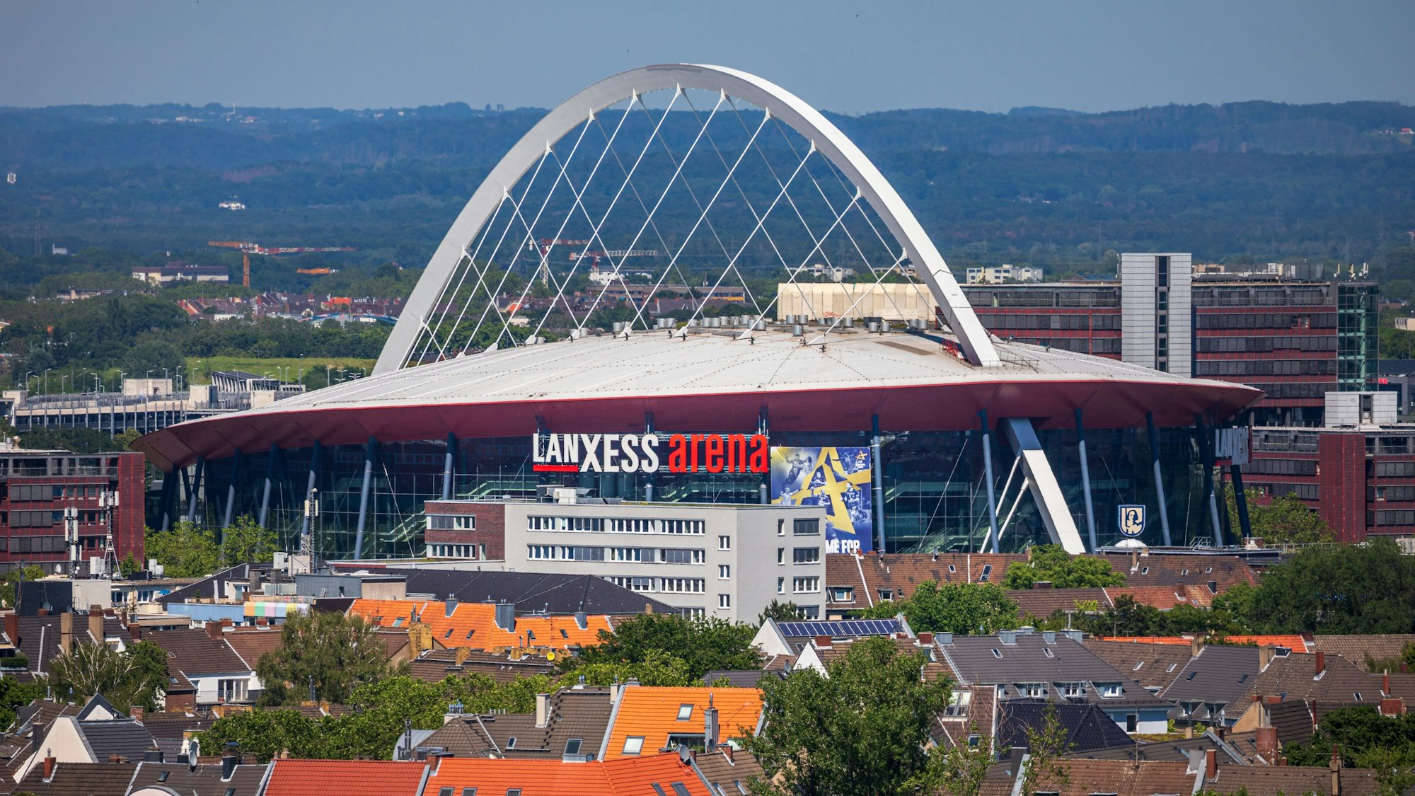 Die Lanxess Arena, früher als Kölnarena bezeichnet, ist inmitten des Stadtteils Deutz zu sehen während der Blick bis weit in das Umland reicht.