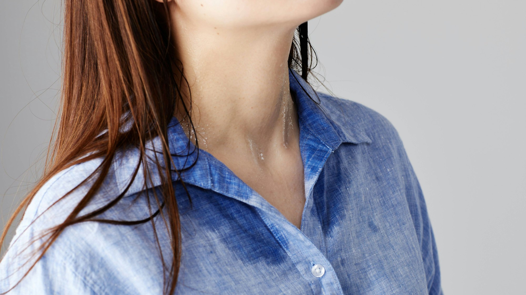 Frau mit Schweißrand am Hemd.