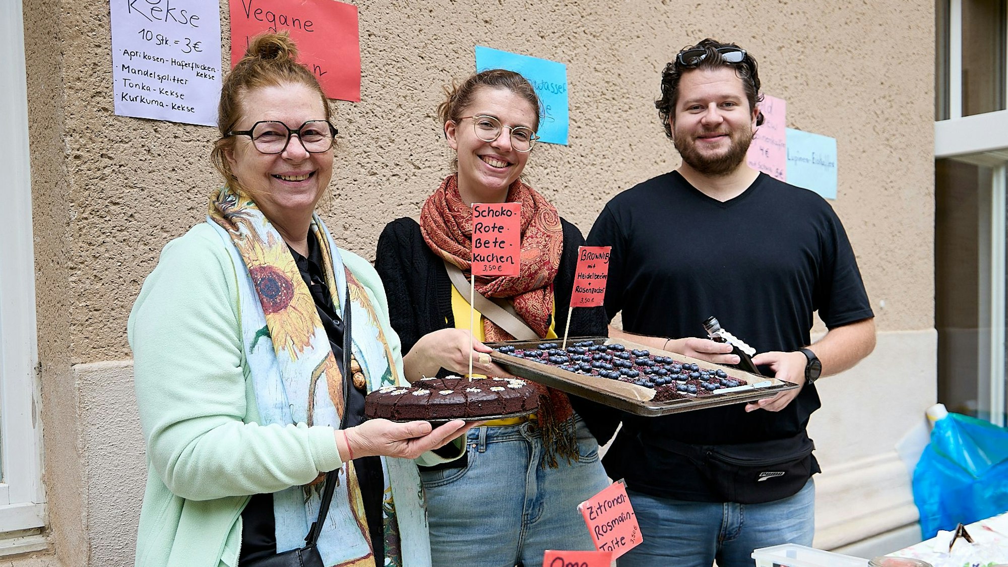Zwei Frauen und ein Mann stehen hinter einem Stand.