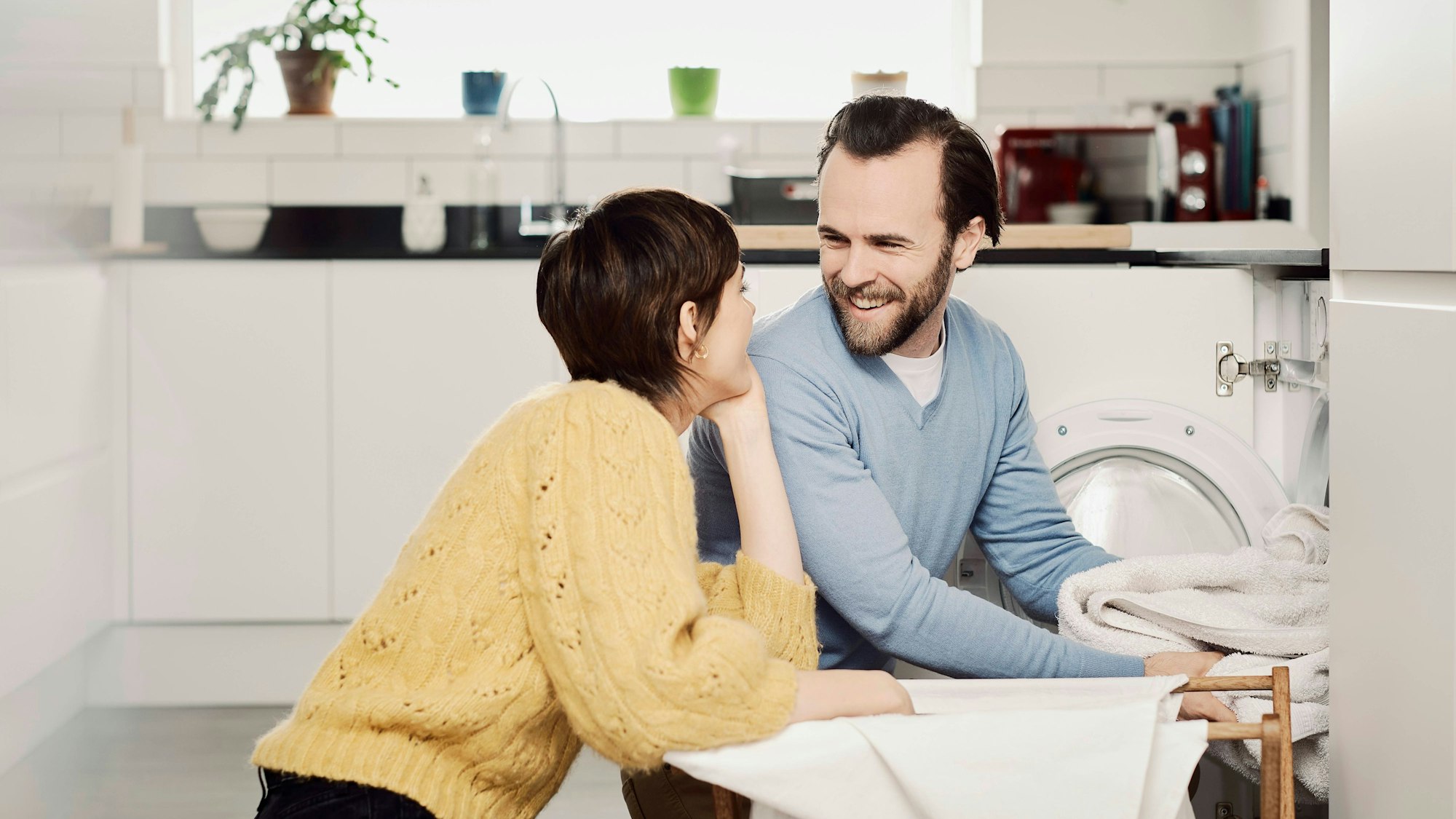 Man und Frau sortieren Wäsche aus der Waschmaschine.