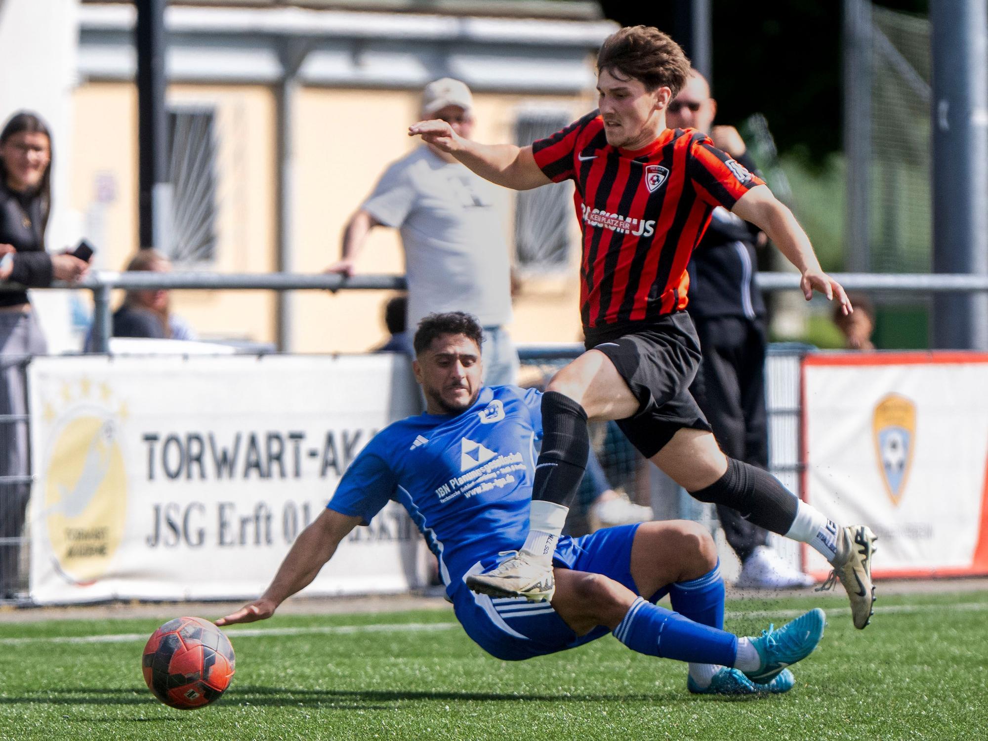 Das Bild zeigt, wie Woywod sich den Ball an seinem Gegenspieler vorbei gelegt hat und über dessen Beine springt.