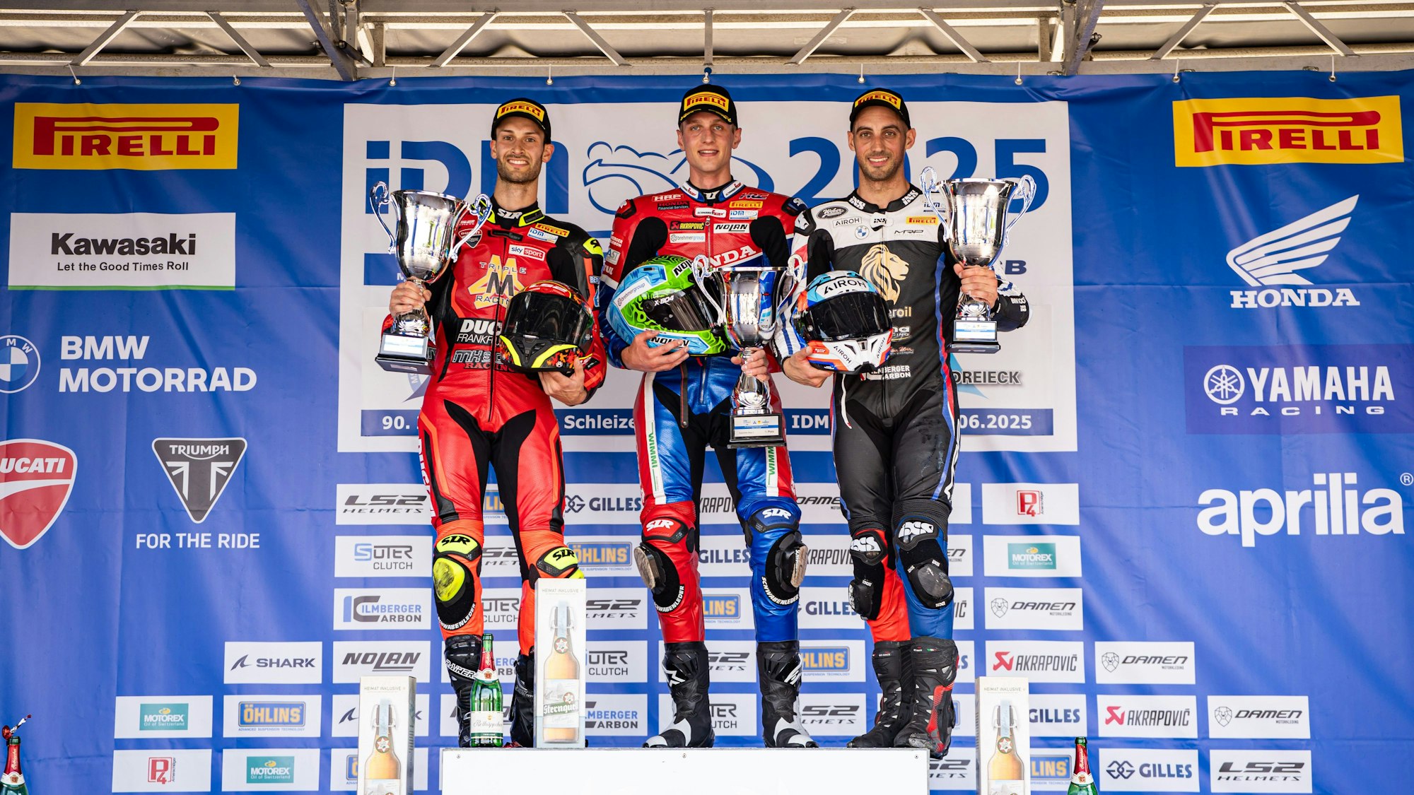 Florian Alt steht auf einem Siegerpodest in der Mitte.