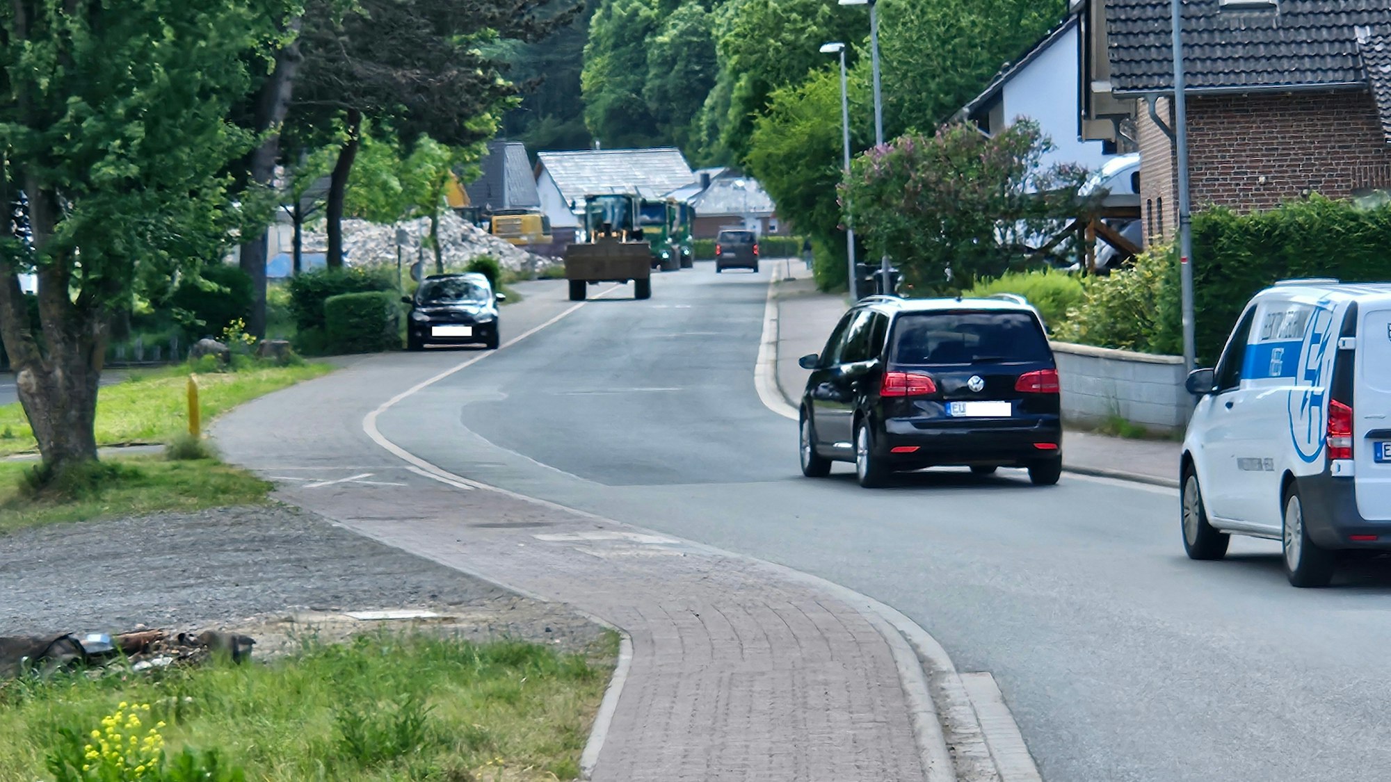 Auf einem geraden Straßenstück fahren mehrere Autos und eine Raupe.